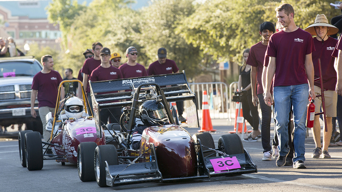 Sun Devil Motorsports, the Formula chapter of the Society of Automotive Engineers at ASU, walk the parade route with one of their race cars.