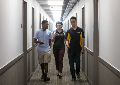 Three students, two men and one woman, walk down a hallway in Tooker House.