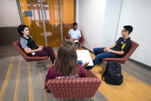 Four undergraduate friends site in a communal lounge area talking in the Tooker House.