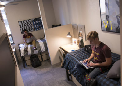 Two young men sit on their beds studying in their Tooker House dorm room