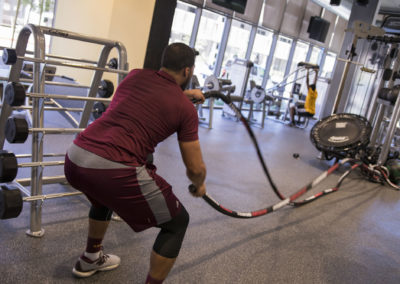 A male student works out with ropes in the Tooker House fitness center