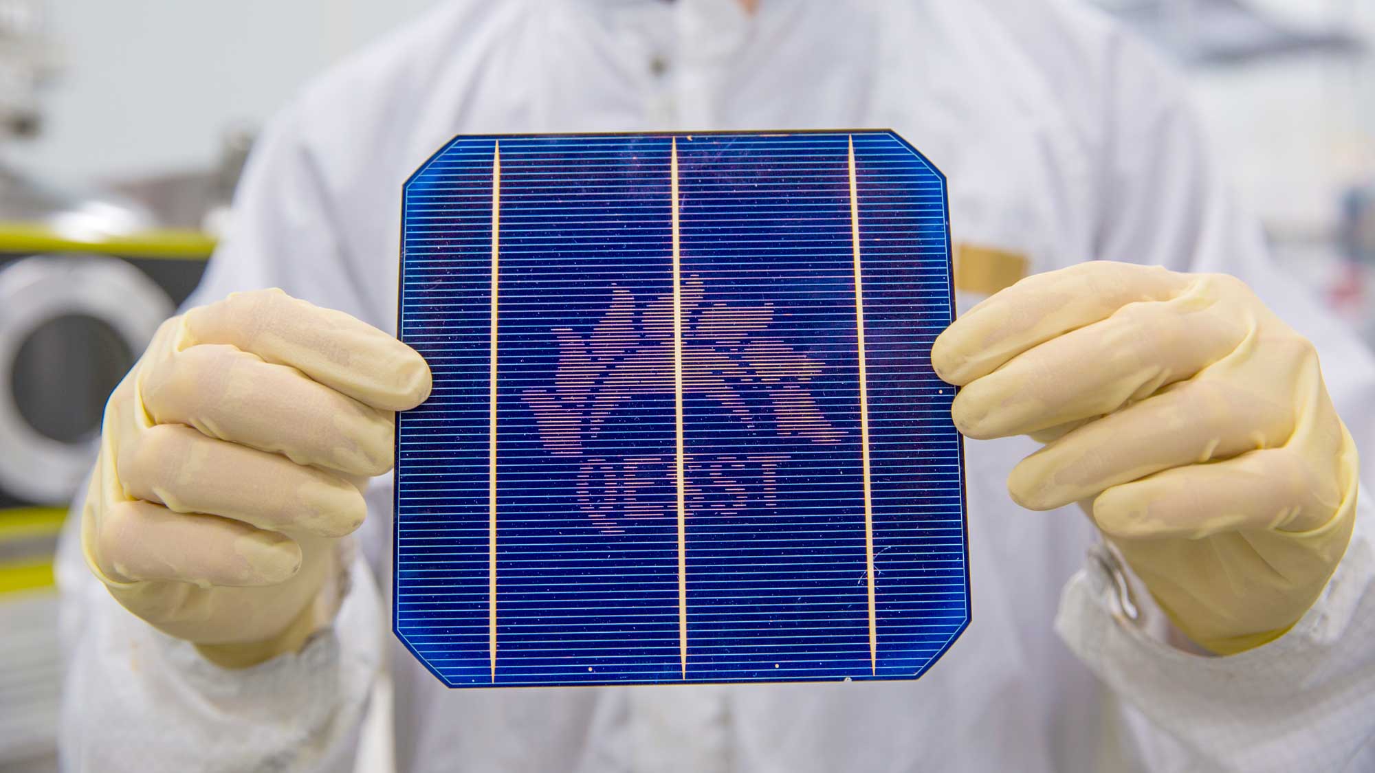 close up of a person holding a solar panel with the QESST logo built into it