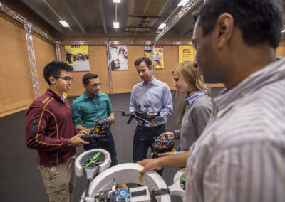 Panos Artemiadis and four other researchers stand together for a photo in the ASU Drone Studio holding devices they test in the facility