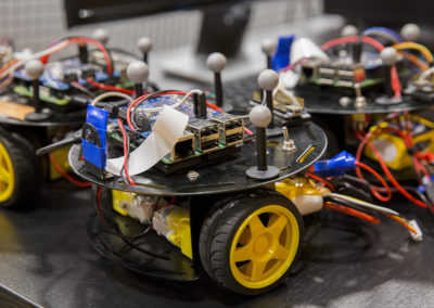 A small, round motorized robotic device on wheels has four gray, ball-shaped sensors mounted on it.