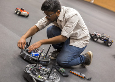 A student kneels down to make an adjustment to customizable drone.