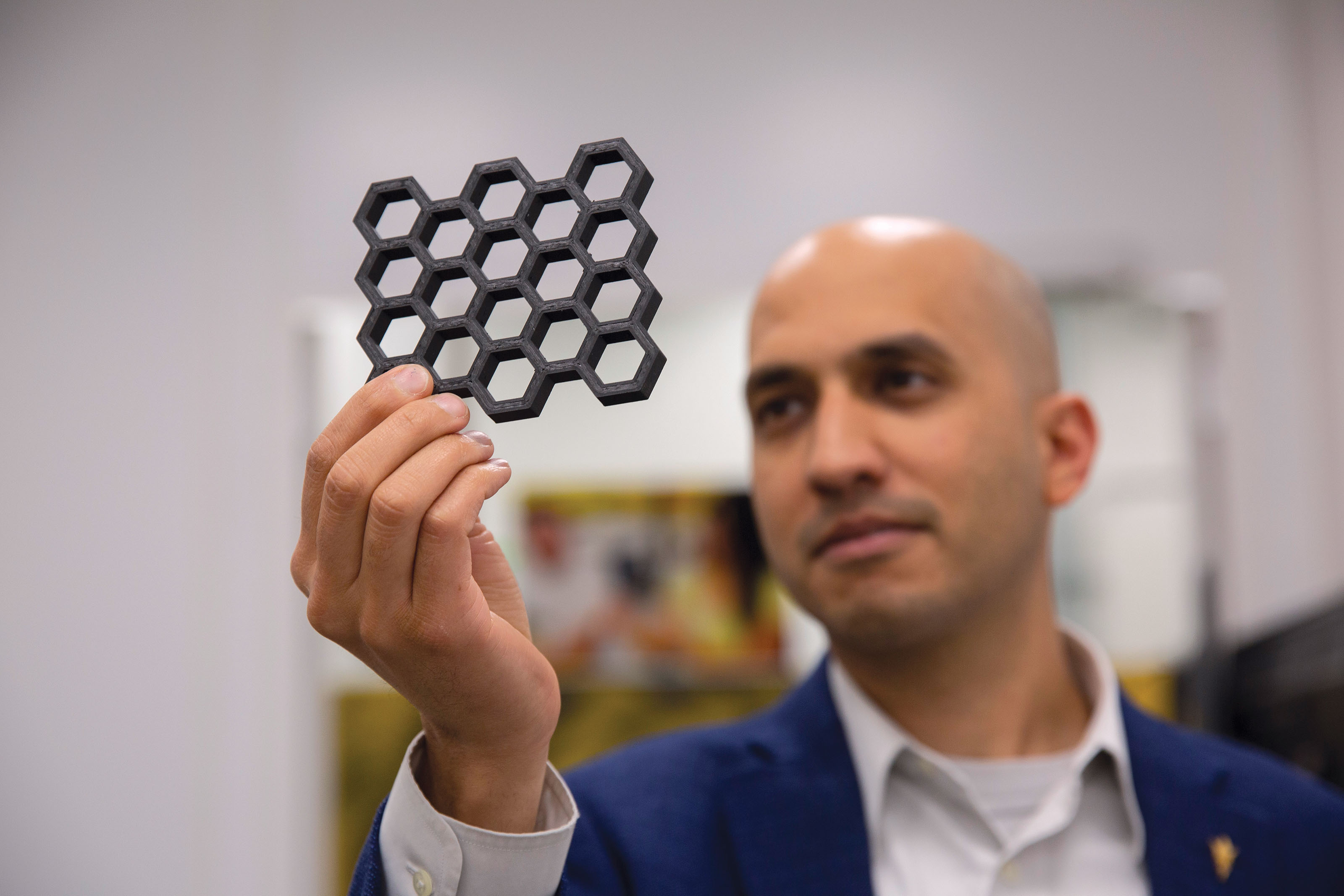 Dhruv Bhate holds a 3D printed hexagonal "honeycomb" shaped object