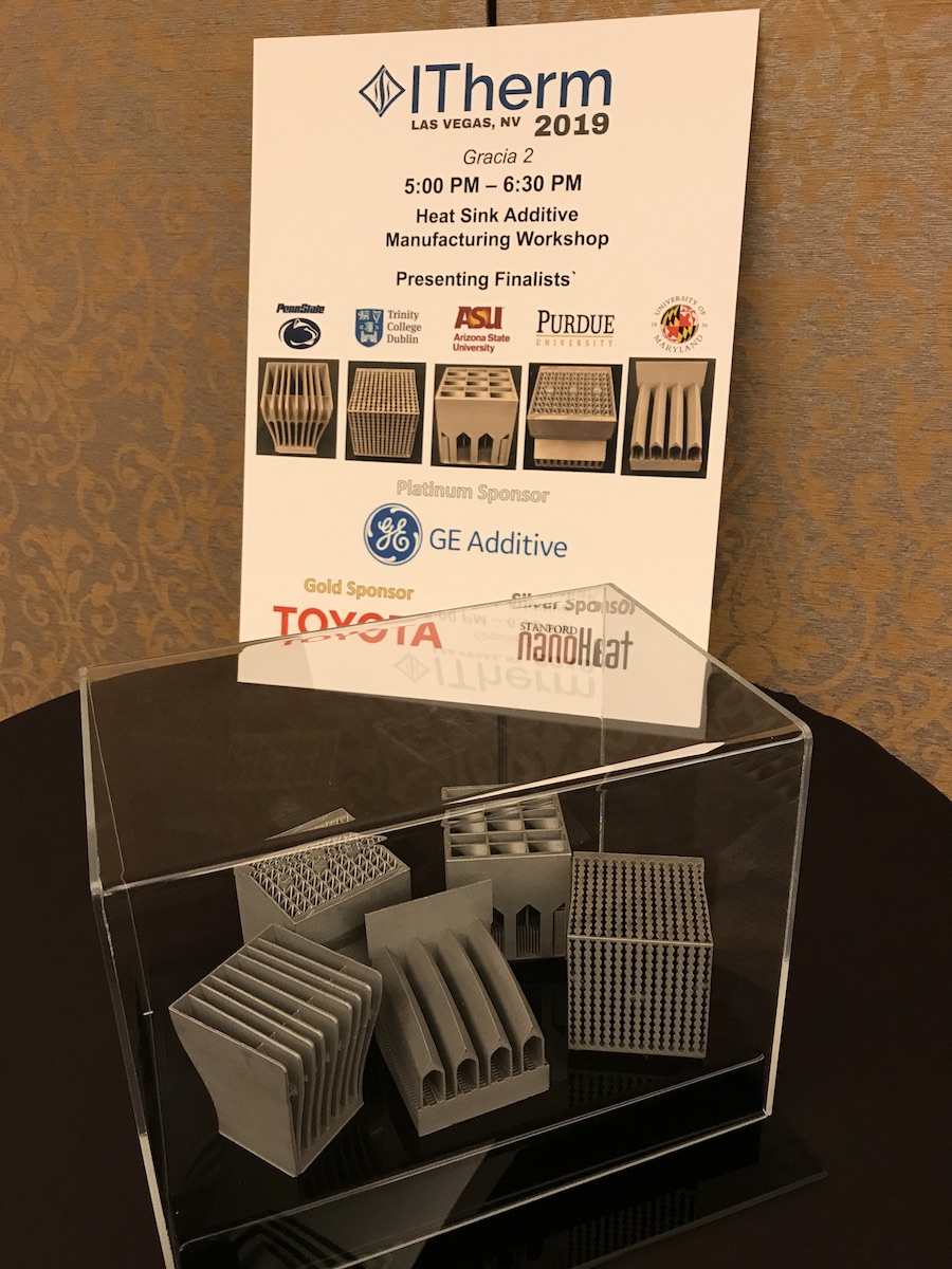 Table with iTherm 3D-printed heat sink competition poster and the five 3D-printed heat sink finalists structures in a plexiglass case