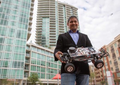 Aviral Shrivastava stands outside in downtown Tempe Arizona holding his small autonomous vehicle