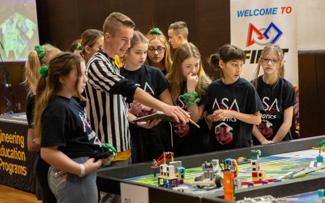 An ASU student volunteers as a judge at the FIRST LEGO League state championship. He discusses a project with the all-girls team.