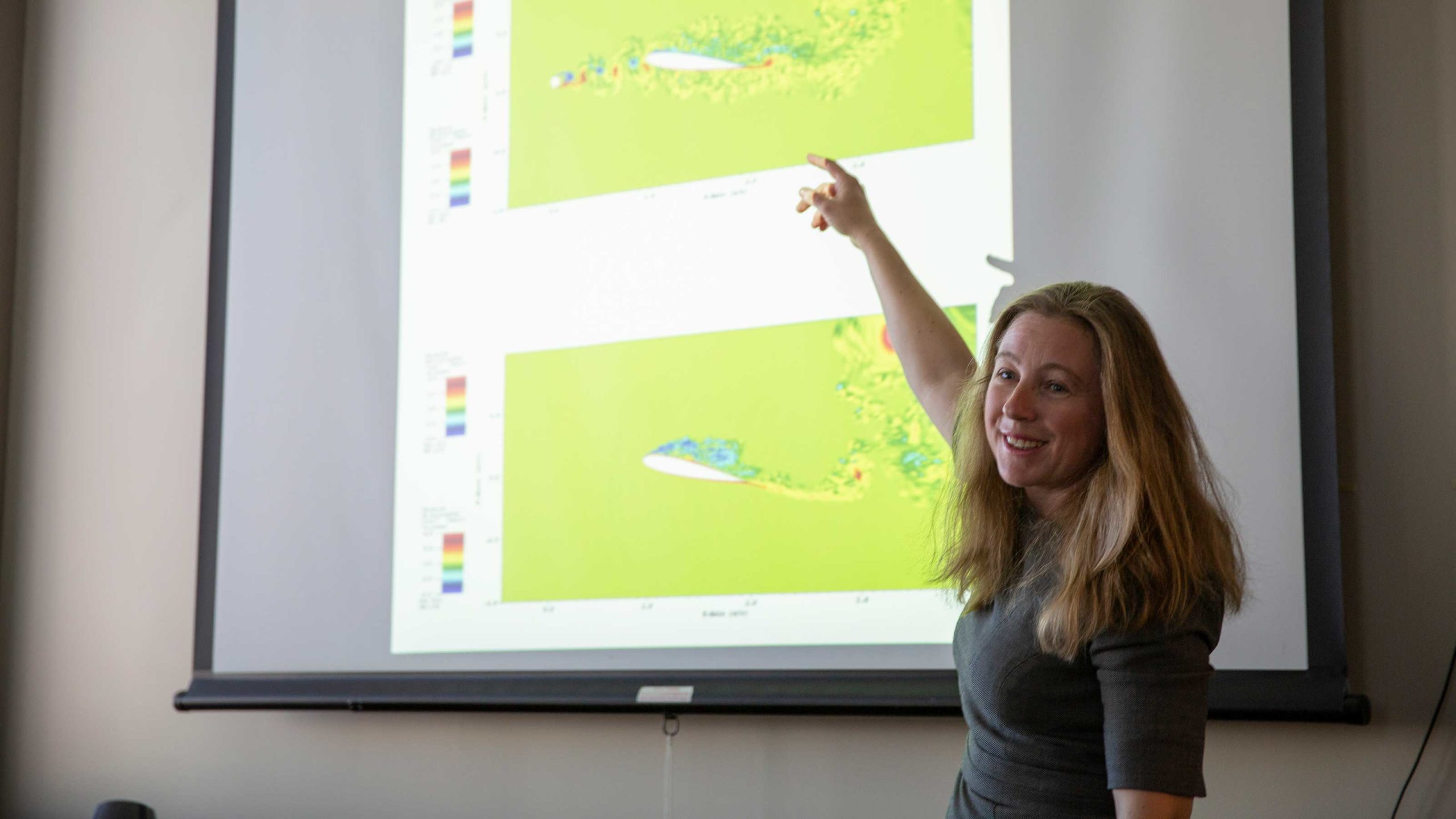 Yulia Peet stands pointing to a graph of data on a screen