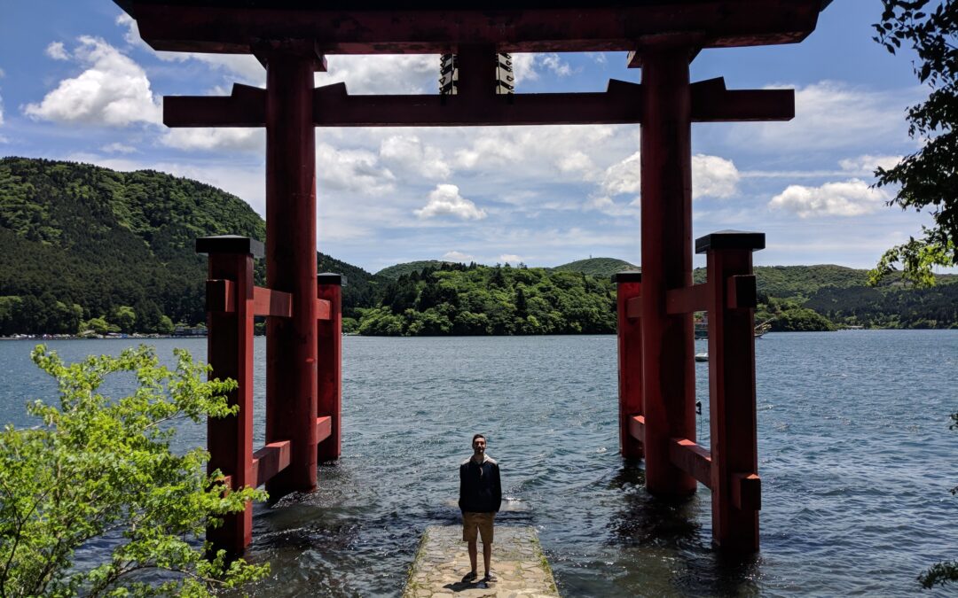 Erick Ciudad stands under a Japanese arch on the edge of a lake