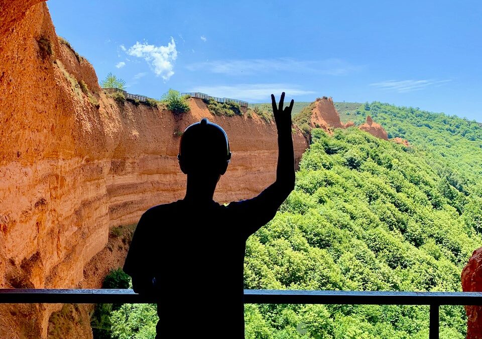 Kameron Moore looks out over a huge red sand cliff and the tops of a forest of trees