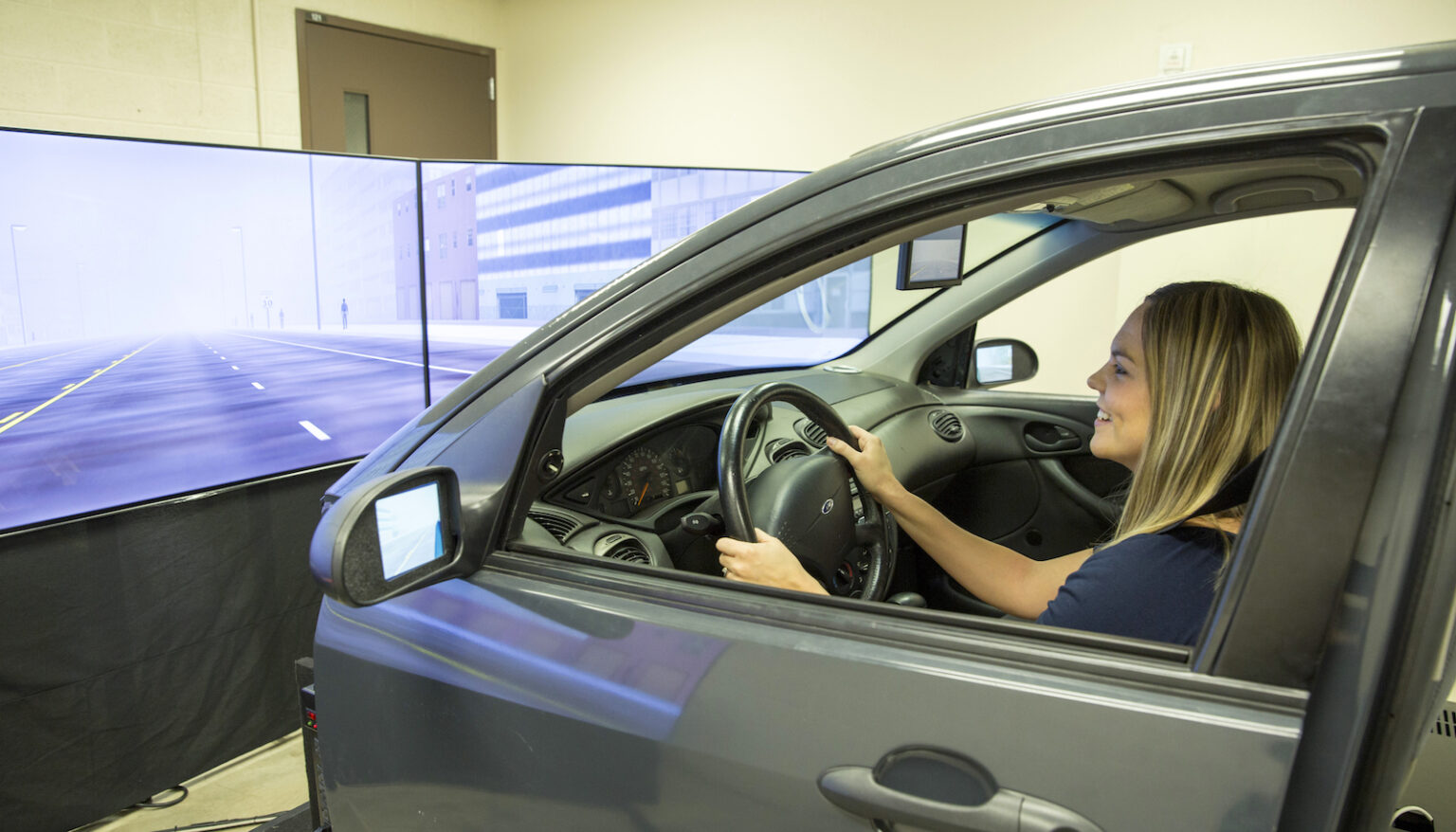 Jaimie McNabb sits in a driving simulator viewing types of visual, auditory and tactile collision warnings