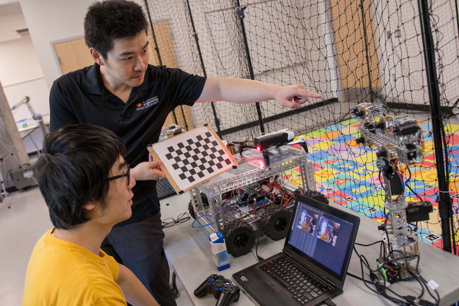 Fulton Schools Assistant Professor Yezhou Yang (standing) directs computer science doctoral student and graduate research assistant Duo Lu in Yang’s Active Perception Group lab at ASU