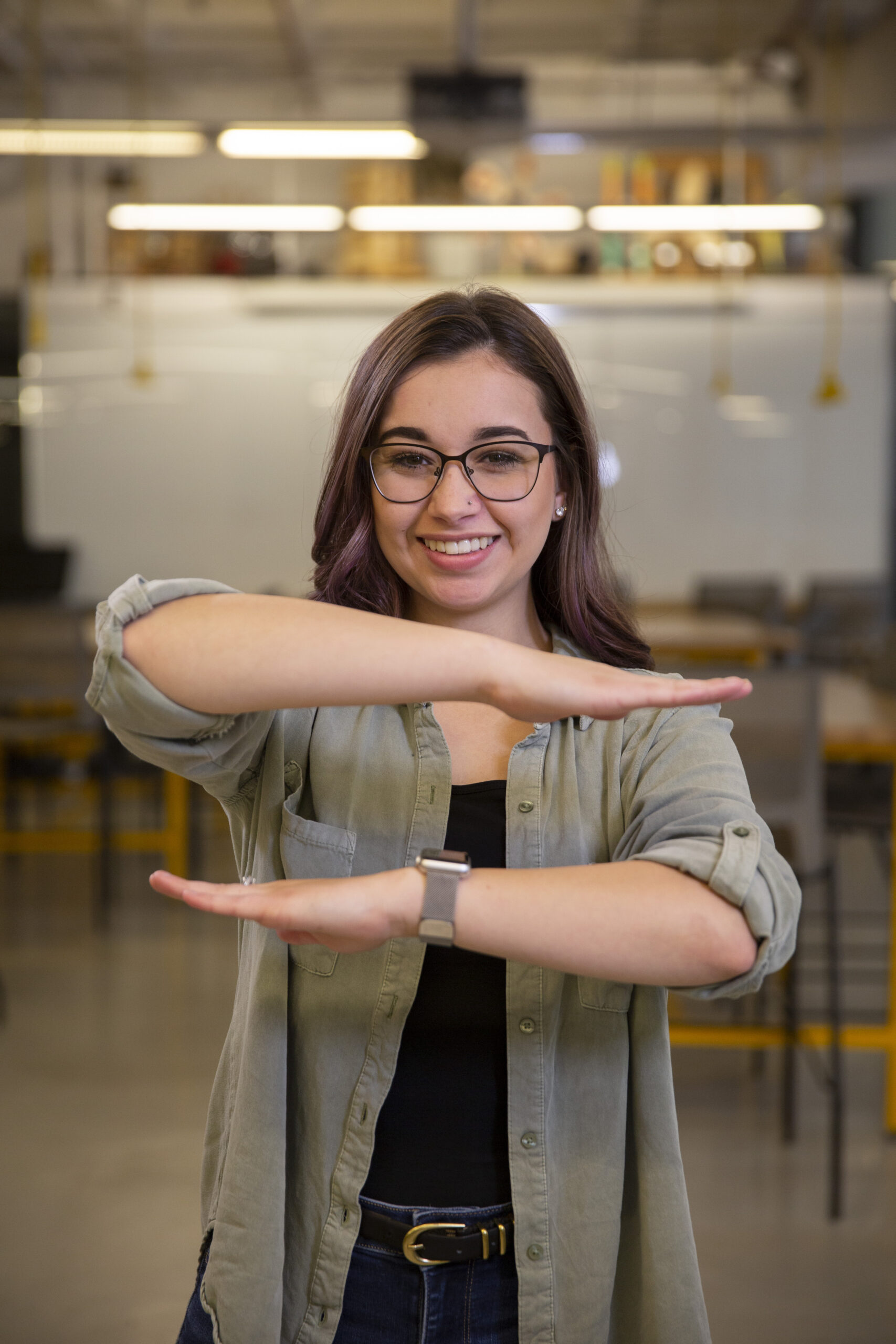 Elizabeth Jones holding her arms parallel to each other in a symbol of equality for women in STEM
