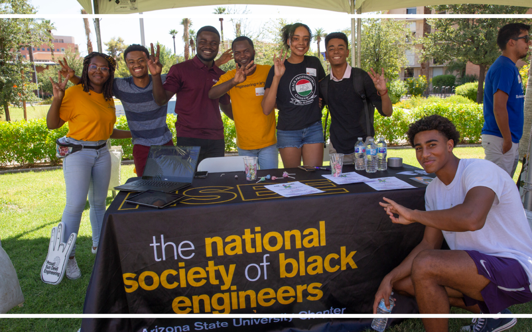 National Society of Black Engineers ASU Chapter members stand together at their table at an event