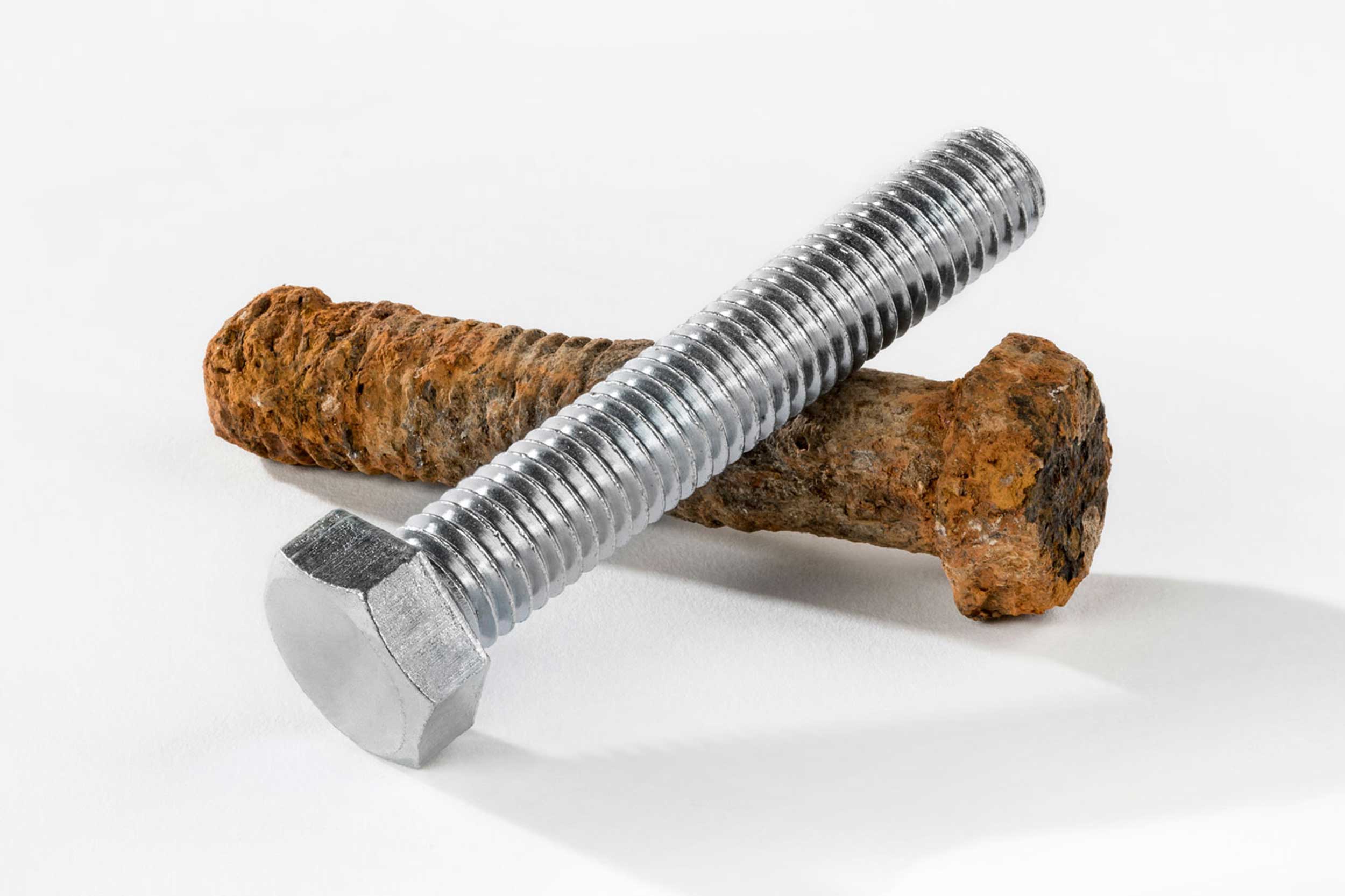 stock image of a brand new metal screw next to a very rusty, corroded screw of the same size