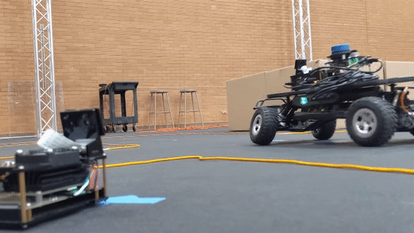 animated GIF showing small, remotely-controlled vehicles on a small track driving in proximity to one another in the ASU Drone Studio during testing