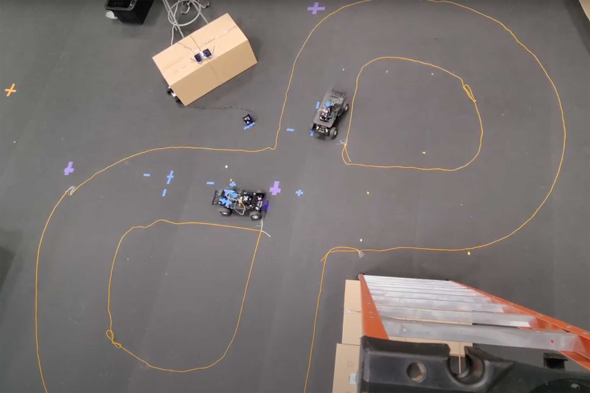 Top-down view of 2 1/10 scale connected autonomous vehicles drive in a figure-eight pattern at ASU’s Make Programming Simple Lab.