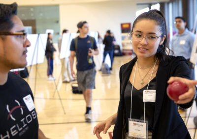 A student talks with a visitor about her research poster at the FURI Symposium