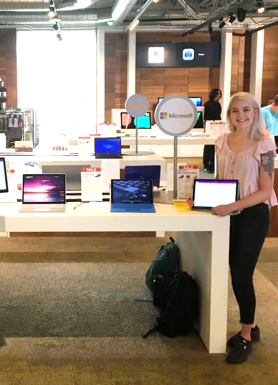 Mary Byron stands at a Microsoft marketing event surrounded by computers