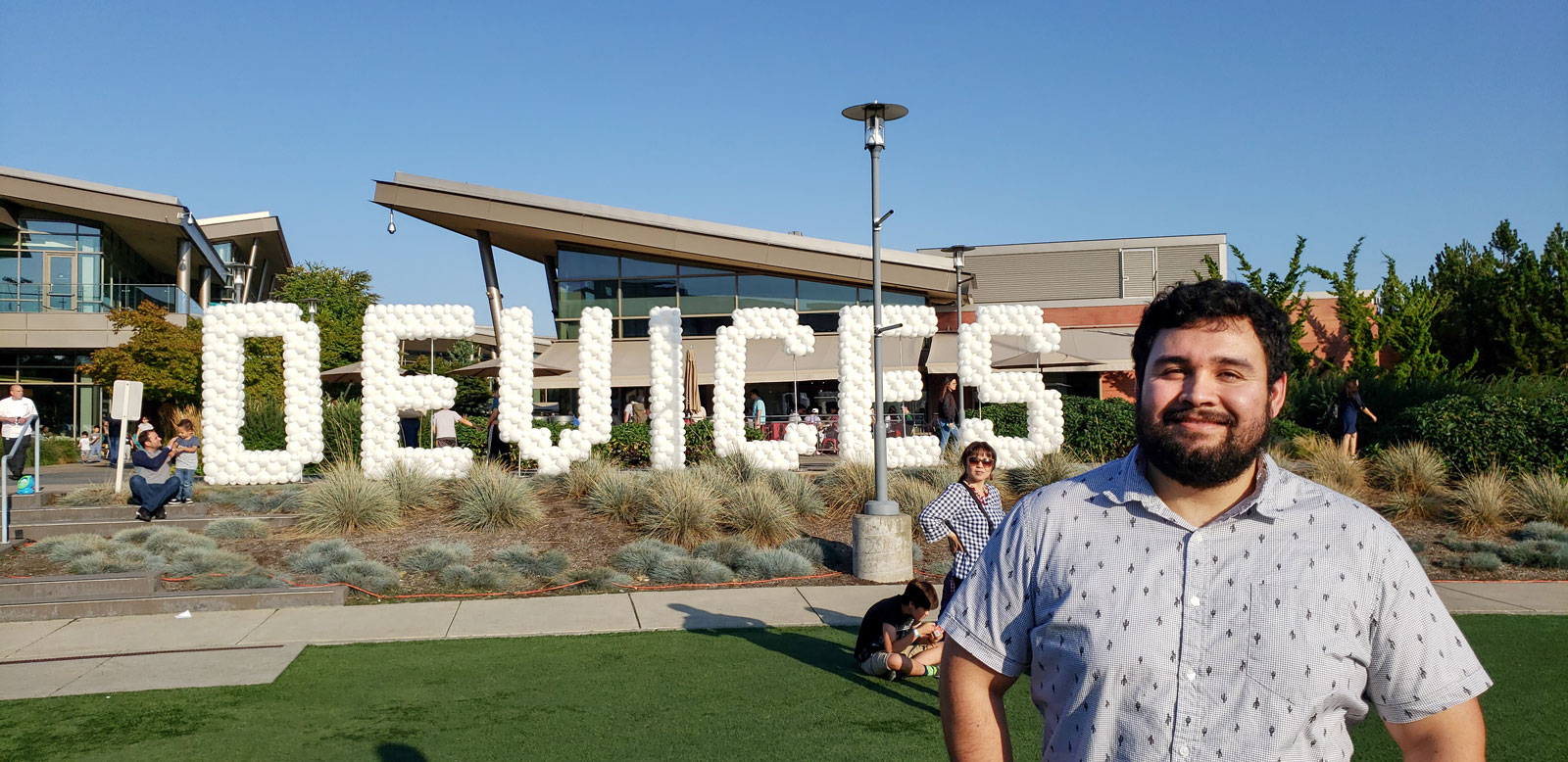 Samuel Perez Diarte stands in front of a Microsoft building with a gigantic "DEVICES" made of balloons in the background