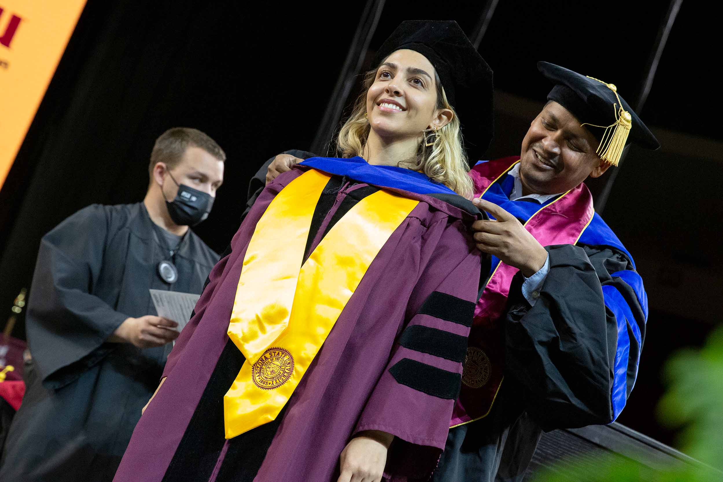 An ASU PhD graduate is hooded by her academic mentor at the Fall 2021 ASU Engineering Convocation ceremony