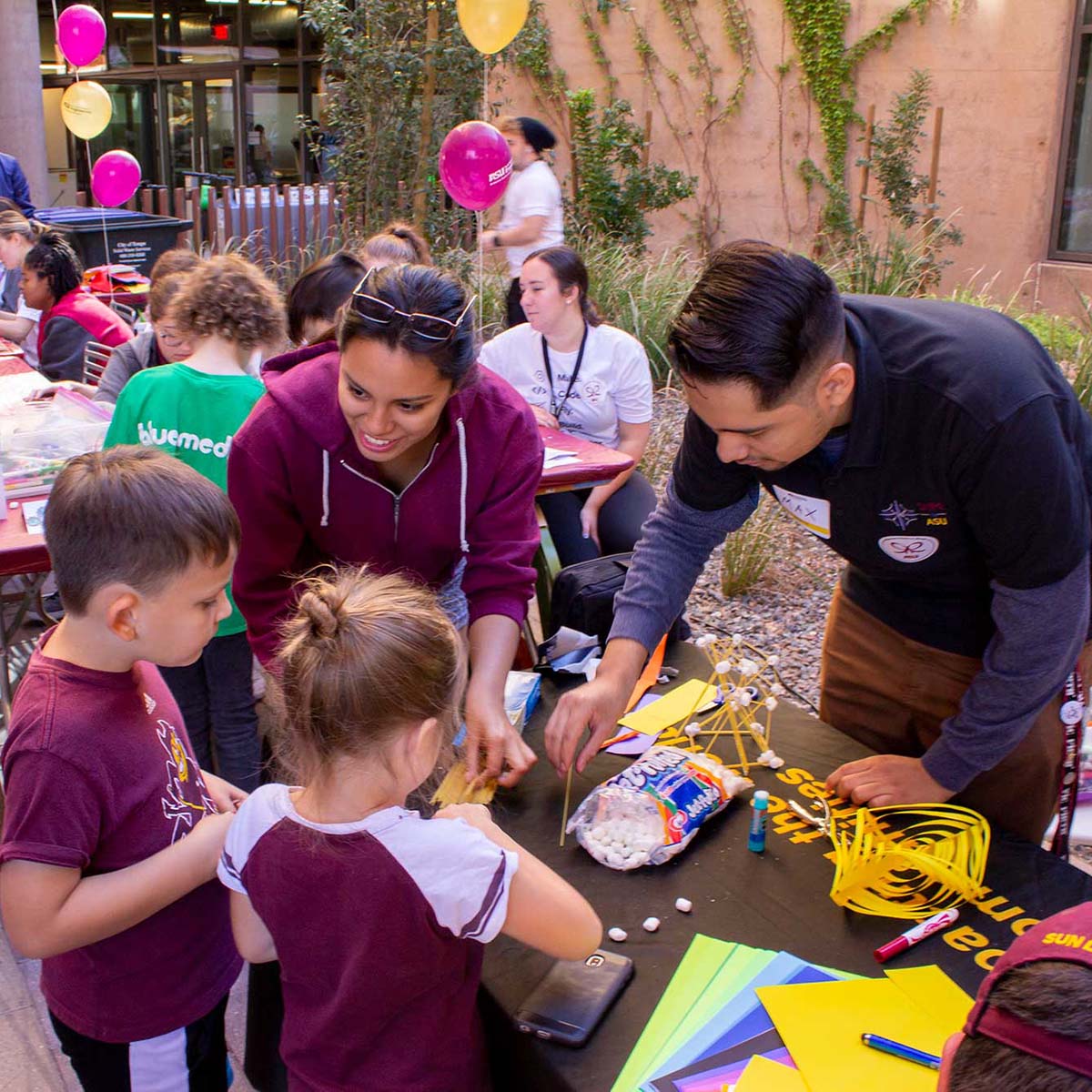Members of the Society of Hispanic Professional Engineers (SHPE) help kids do a project at their activity table during ASU Open Door