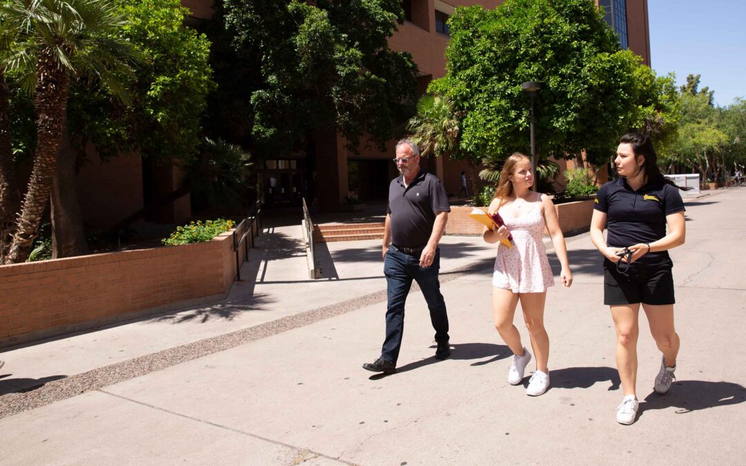 A Fulton Ambassador gives a tour to a prospective student and her father. They walk along Palm Walk on the Tempe campus