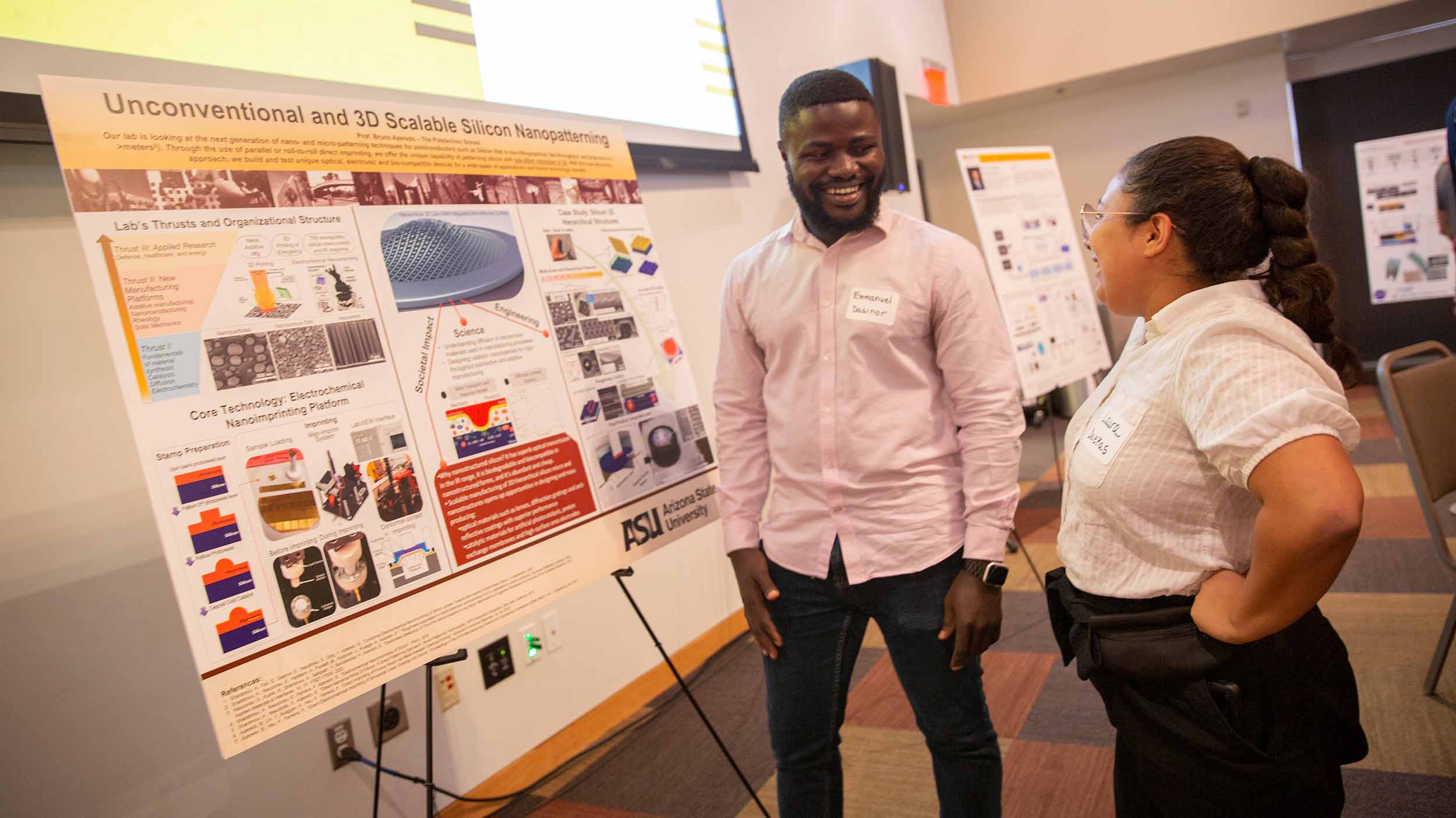 Mechanical engineering Graduate Research Associate Emmanuel Dasinor stands next to Laura Duenas Gonzalez by their research poster at the School of Manufacturing Systems and Networks open house event