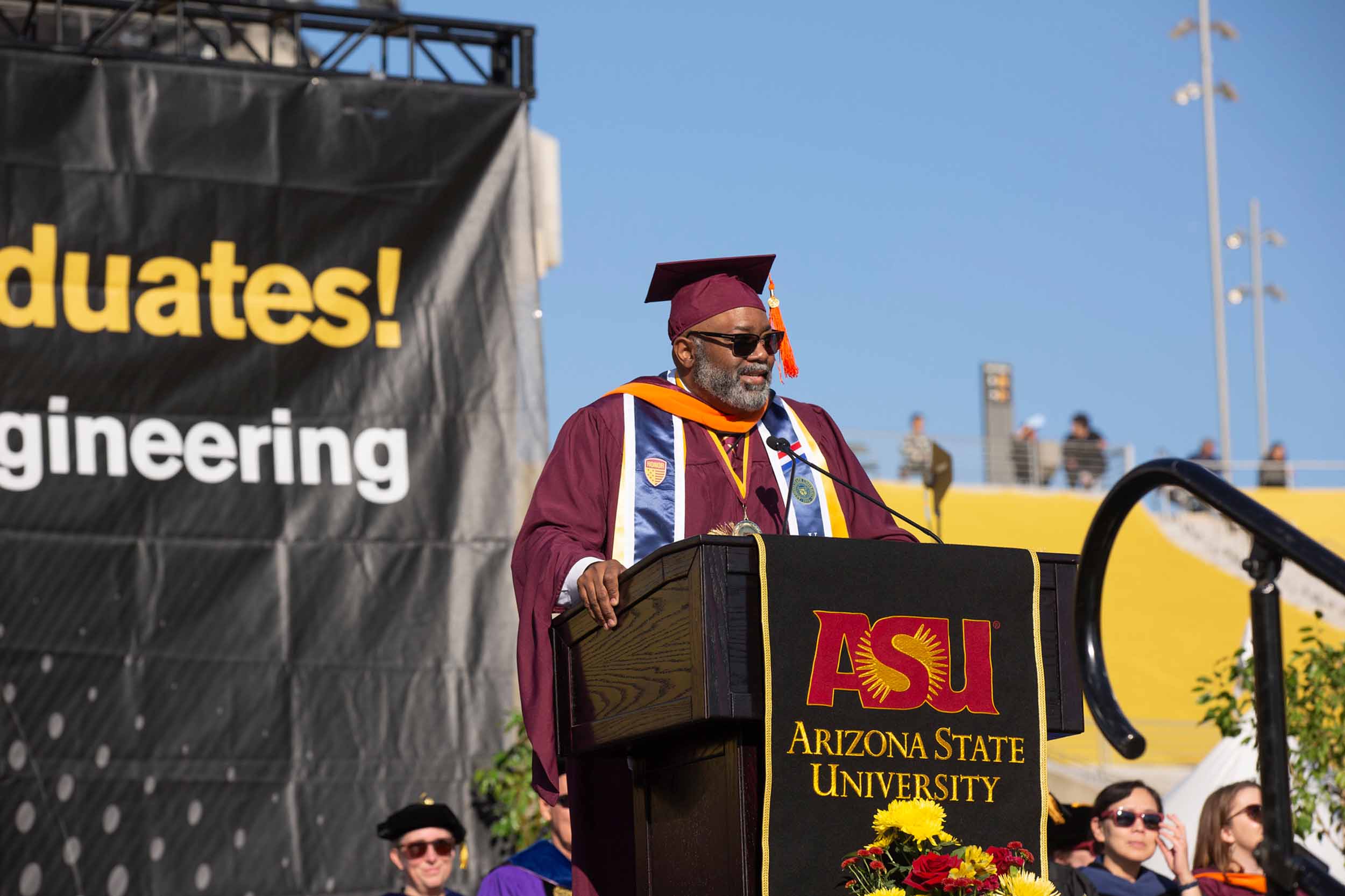 Melvin "Mitch" Gatewood, the Fall 2022 ASU Engineering Convocation speaker, stands at the podium delivering his message in Sun Devil Stadium.