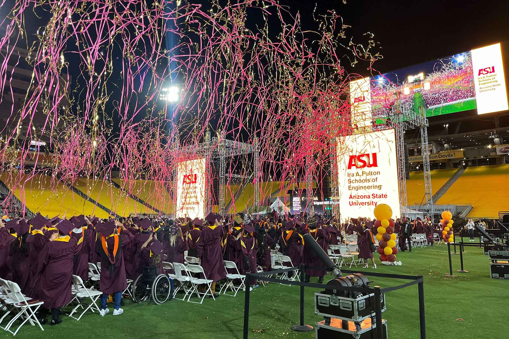 A view within Sun Devil Stadium of the Class of 2023 celebrates the end of their Convocation ceremony. Maroon and gold streamers fill the air, and the crowd is erupting in joy.