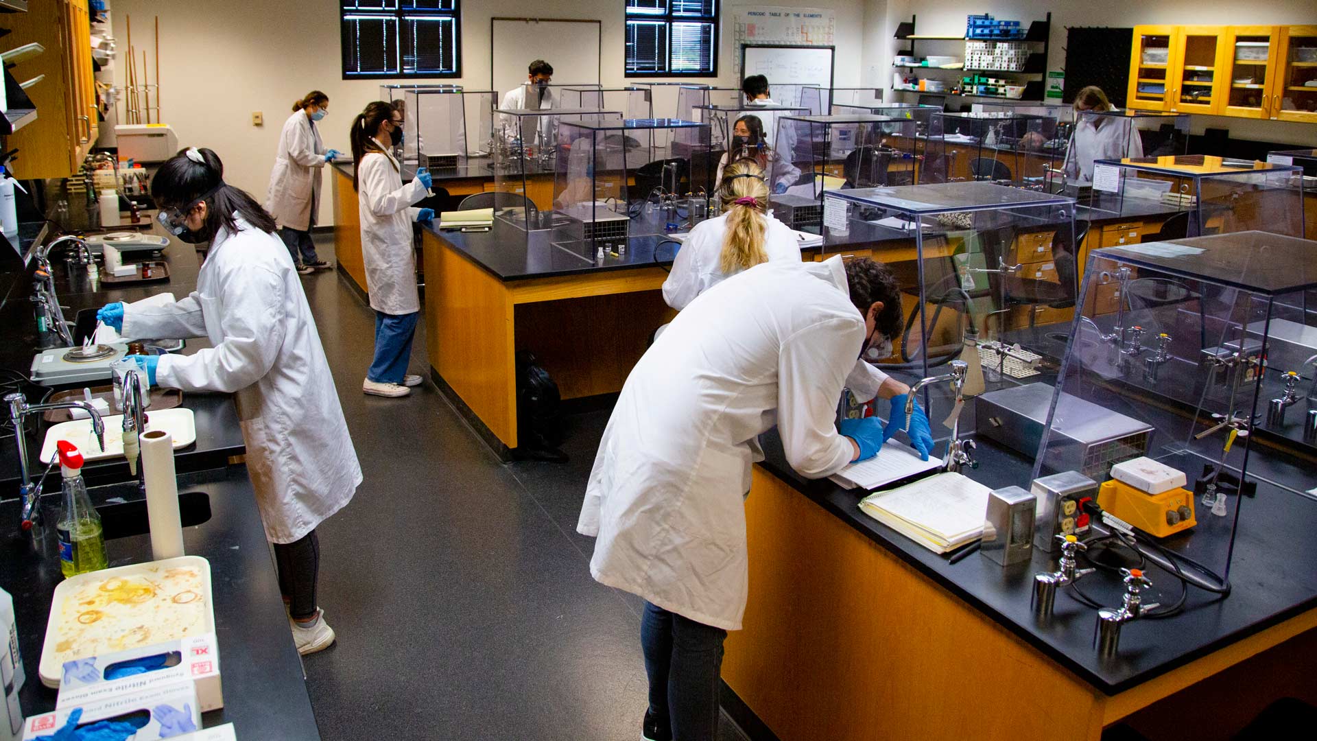 10 students wearing protective laboratory garb, work at lab benches in an organic chemistry lab on ASU's West campus