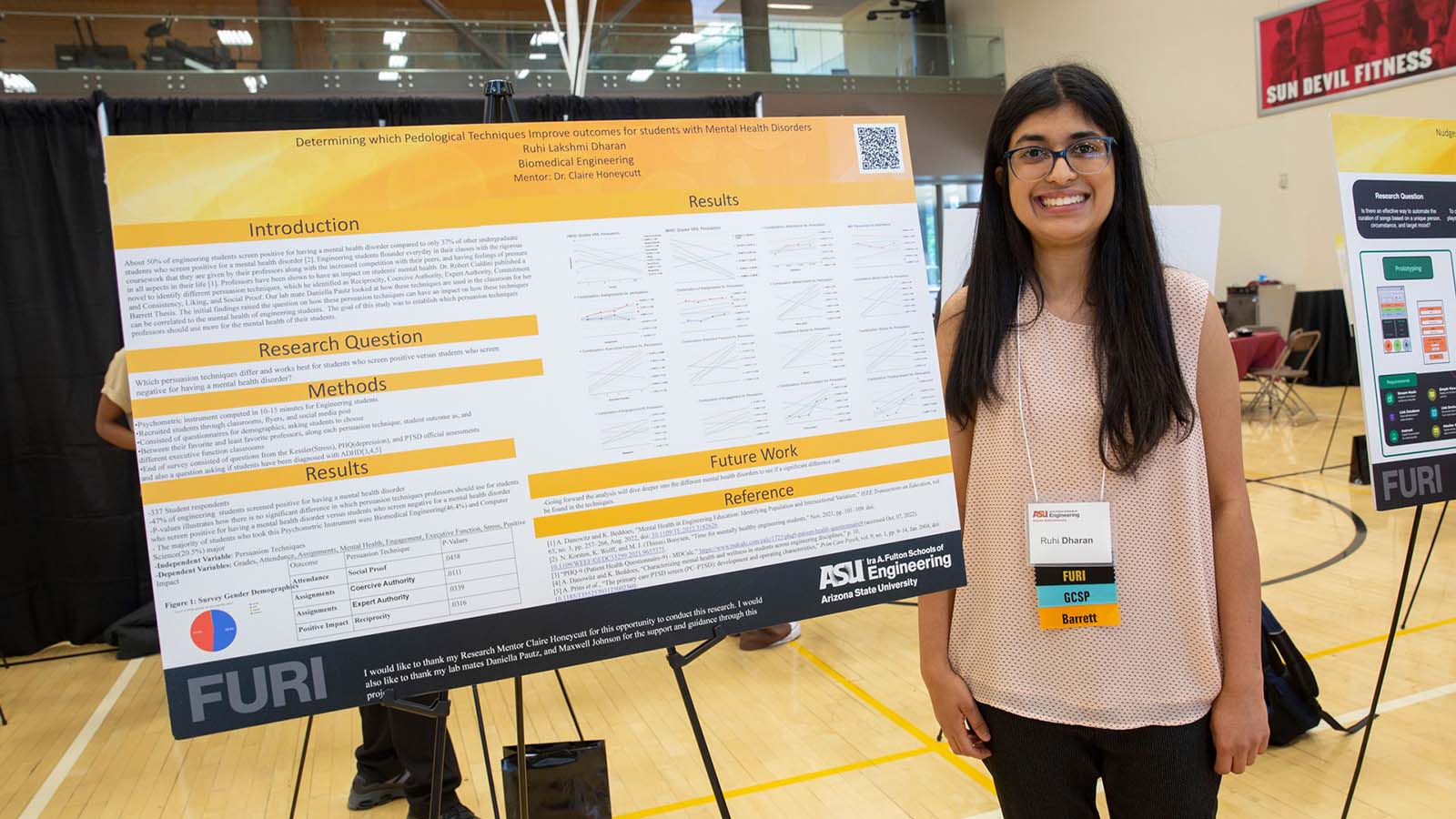 An ASU Engineering student researcher stands next to her research poster at a student research presentation event.