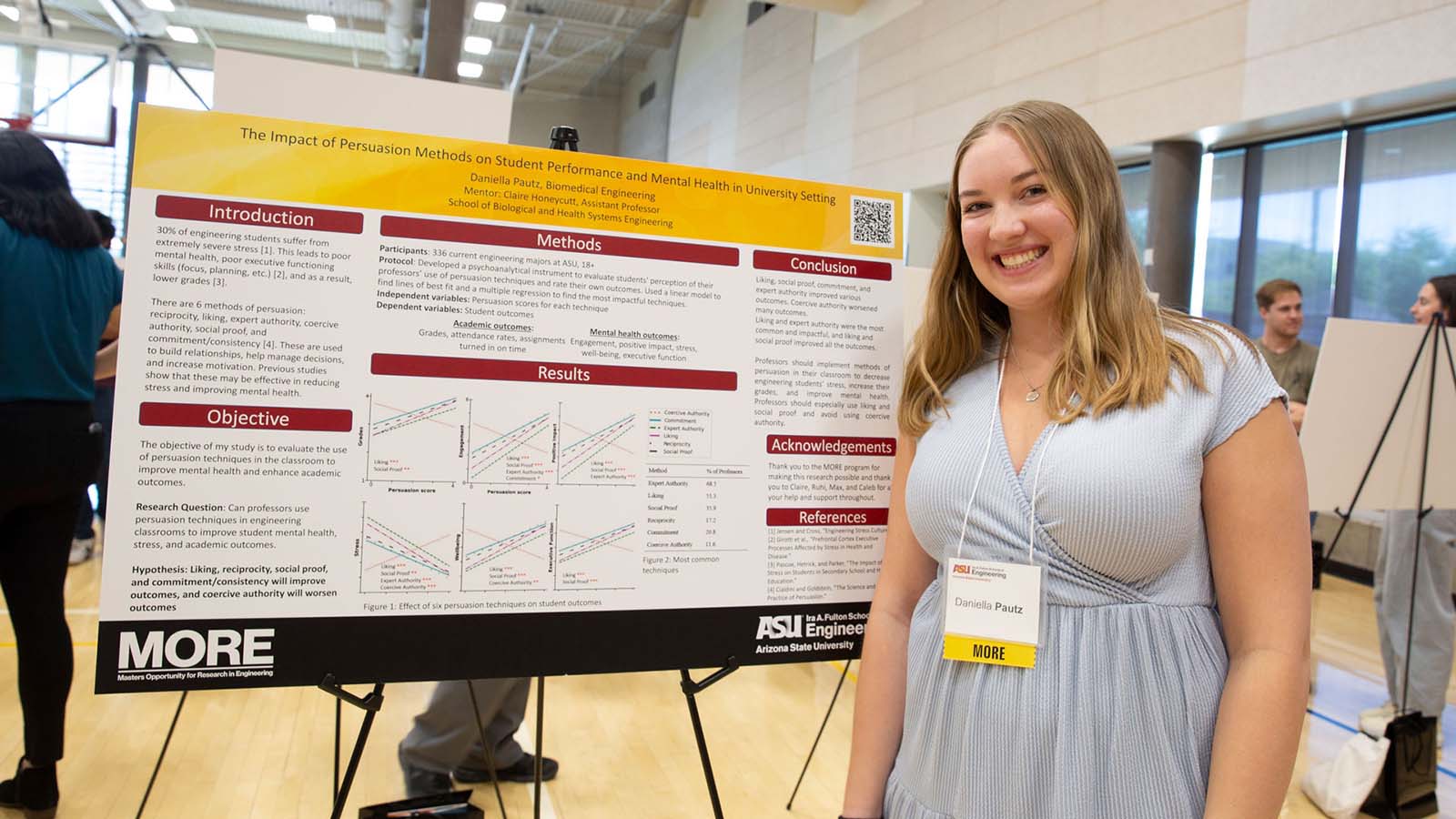 An ASU Engineering graduate student stands next to her presentation poster at a student research event.