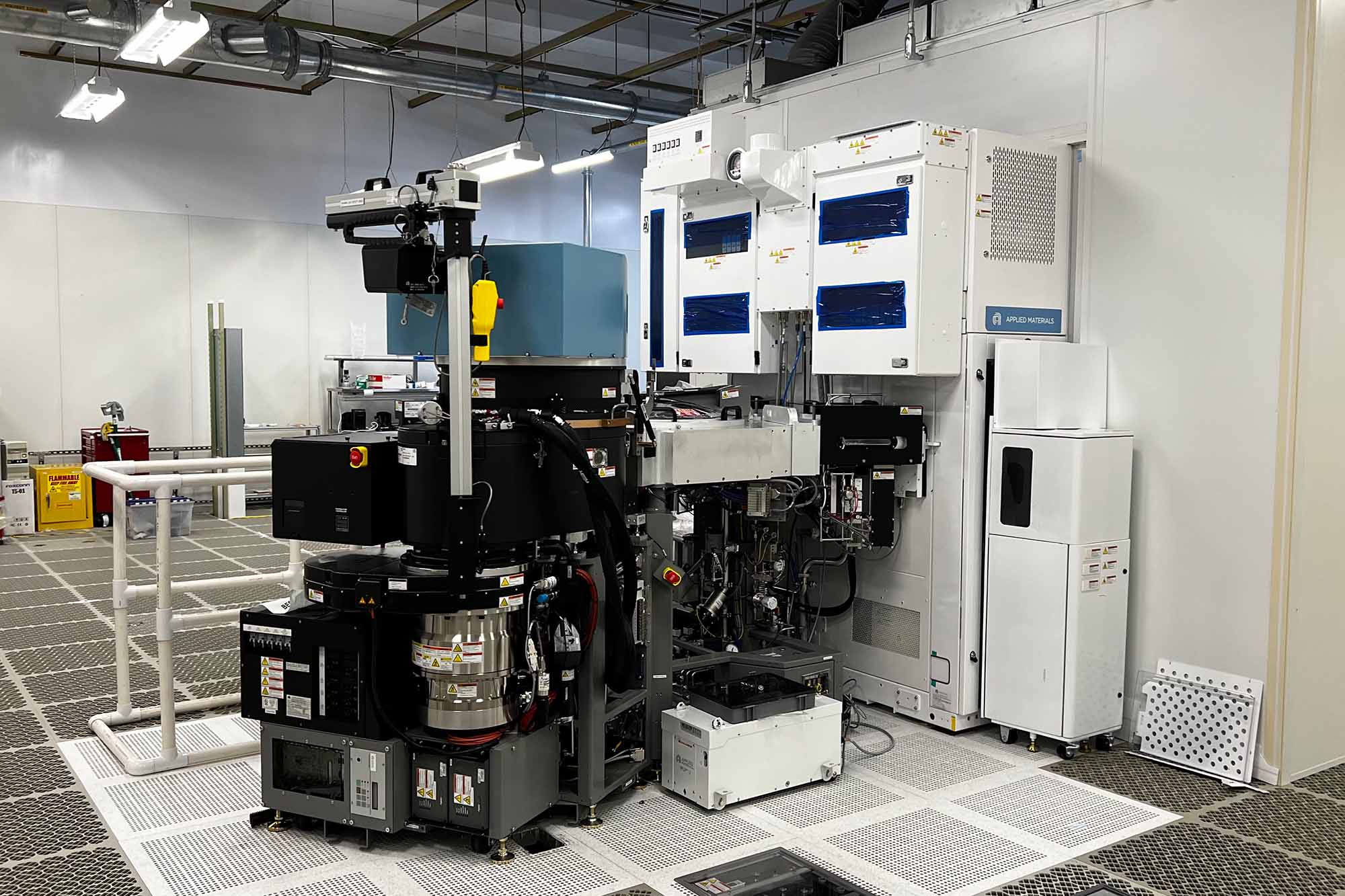 A black, white and blue piece of electronic manufacturing equipment, a reactive ion etcher which can be used in the process of making semiconductors, sits in a large open room.