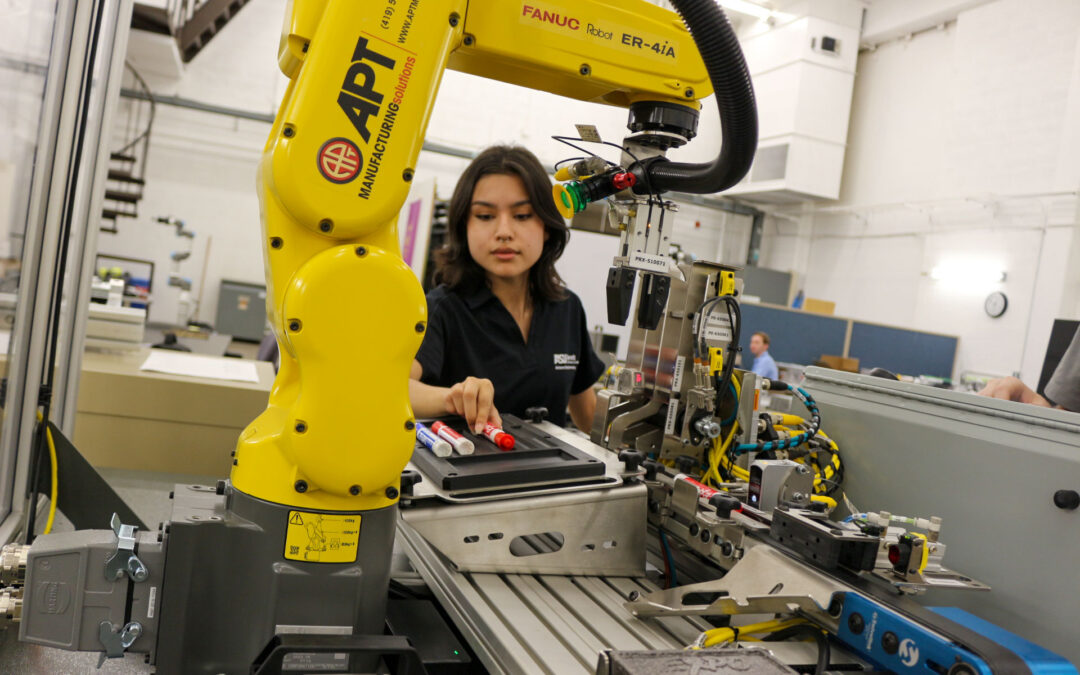 A student operates a large robot arm.