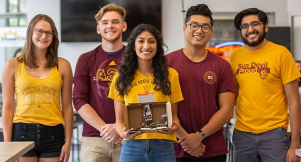 Five students pose together with an engineering project.