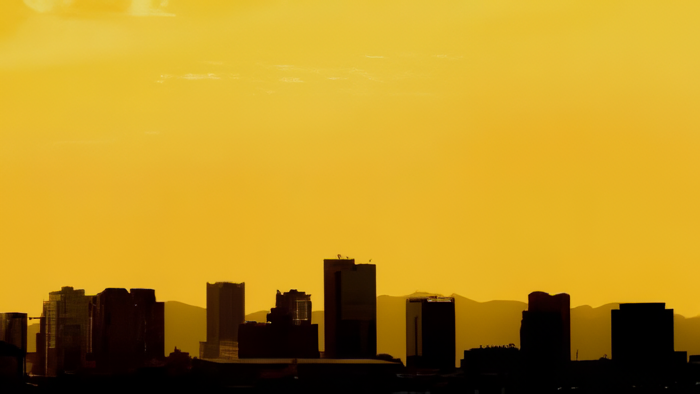A cityscape in front of a golden sky.
