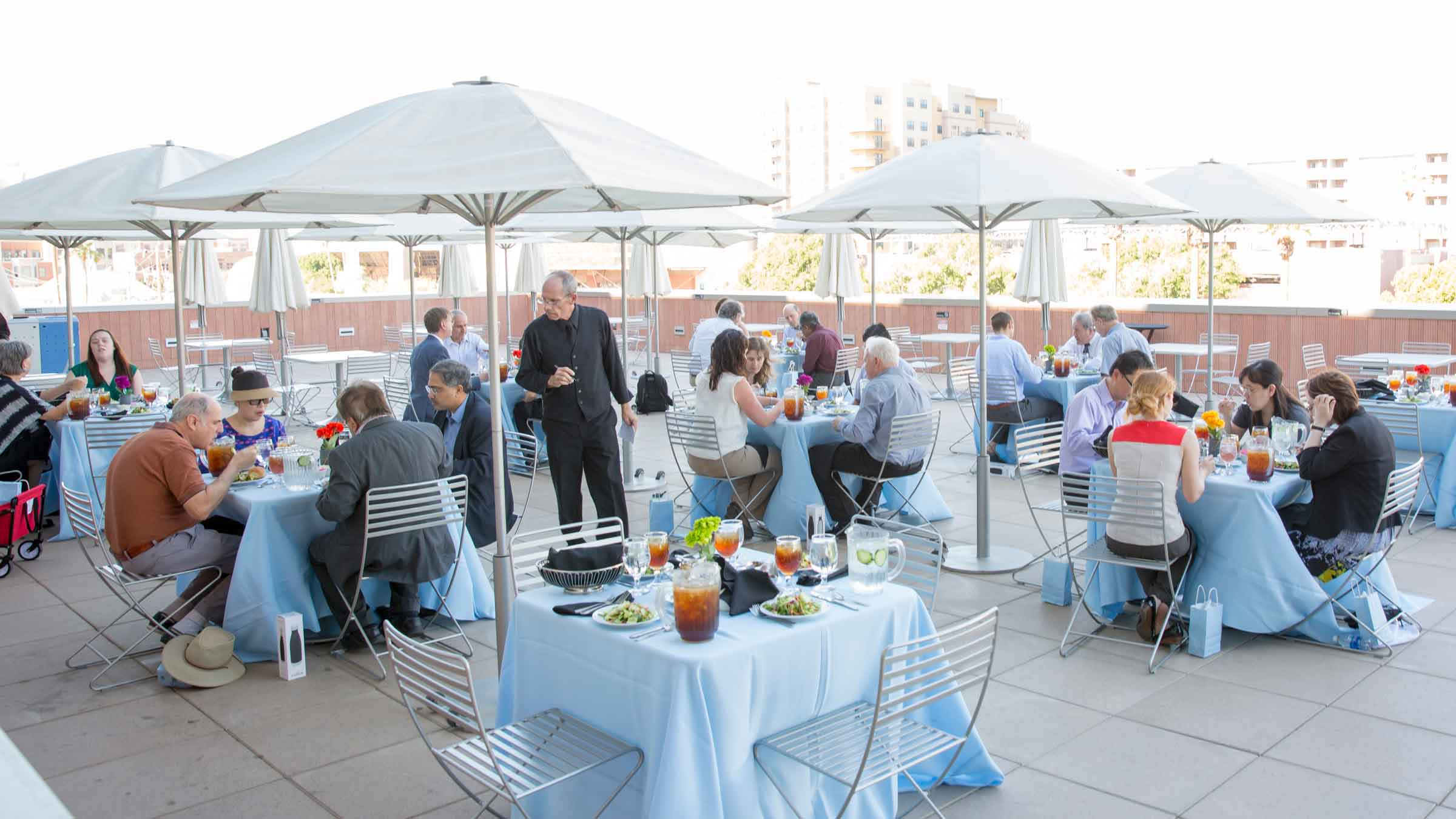 A group of about 40 ASU Engineering faculty sit outdoors around tables eating at an event.