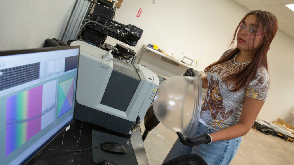 A woman presses a glass half-sphere coated with Swift Coat's coating to an analysis machine which provides feedback on the screen next to it.