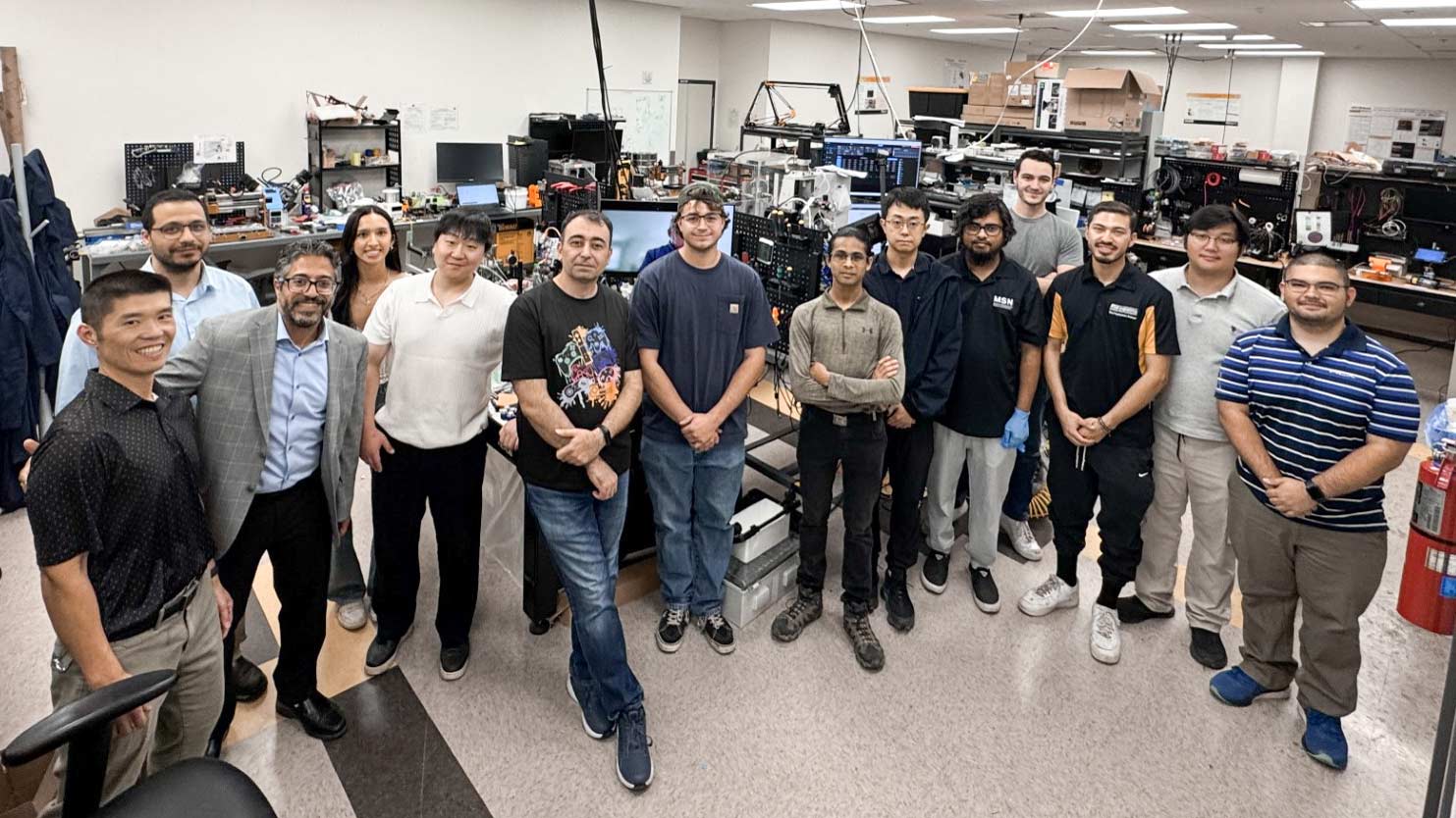 A group of people standing in a room filled with computers, engaged in discussion and collaboration.